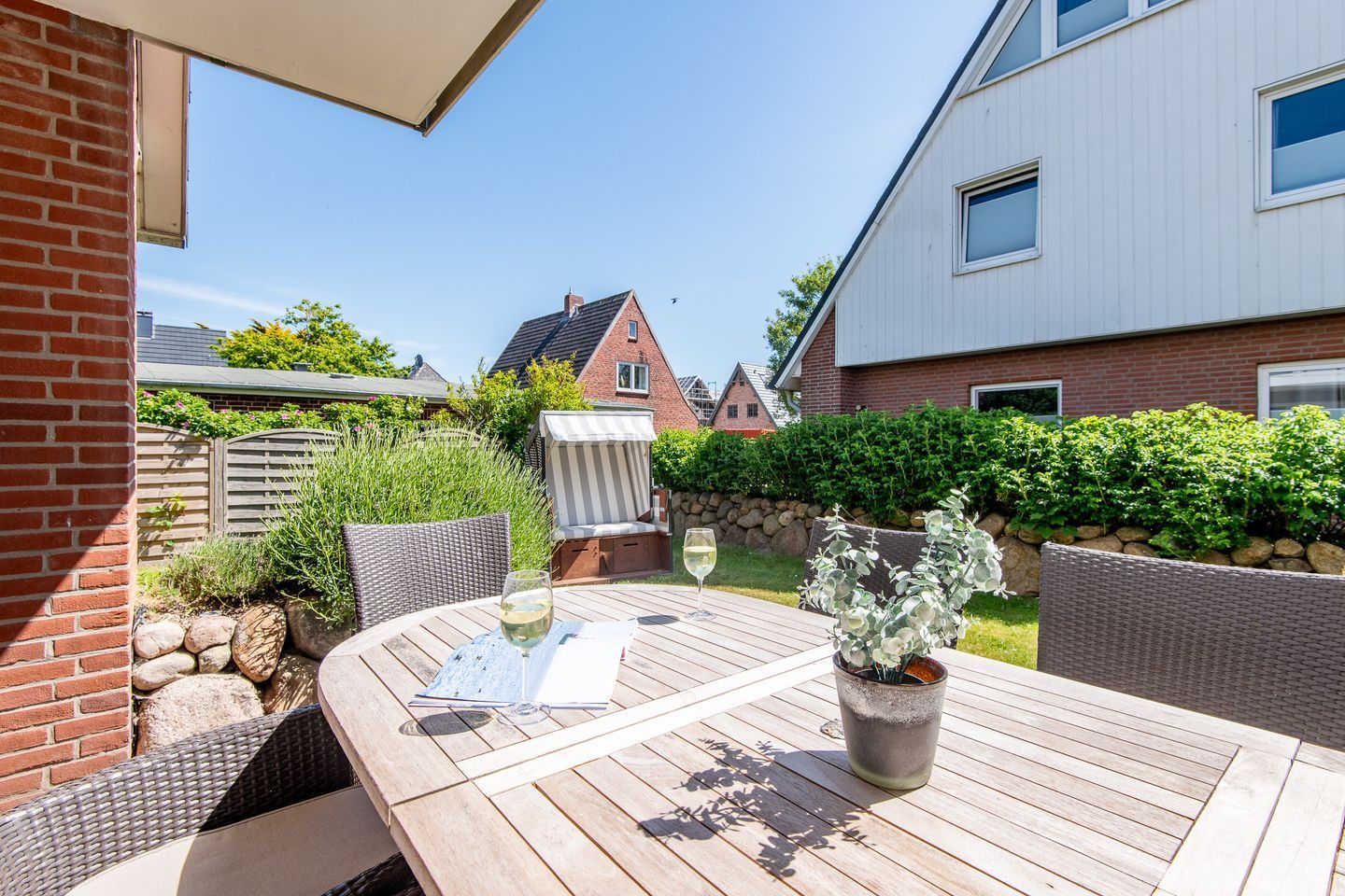 A patio with a table, chairs, and a glass of wine.