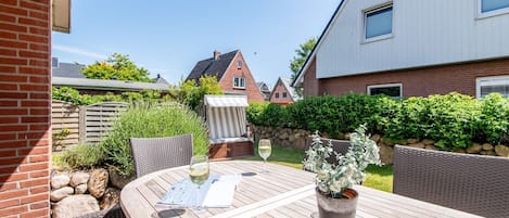 A patio with a table, chairs, and a glass of wine.