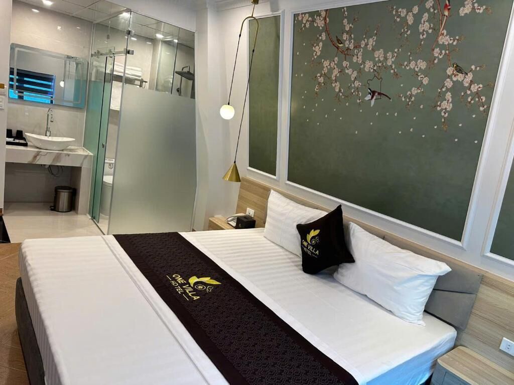 A hotel room with a bed, a nightstand, a mirror, a shower, and a wall with a floral mural.