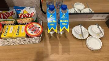 Montaje de desayuno buffet con bocadillos, agua embotellada y platos desechables.
