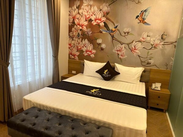 A hotel room with a bed, a bench, a nightstand, and a wall with a floral mural. - One Villa Hotel 5 (Hanoi)