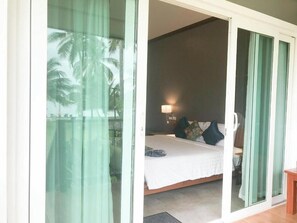A bedroom with a bed, a nightstand, and a lamp. - Koh Yao Yai Sea Breeze House (Ko Yao)