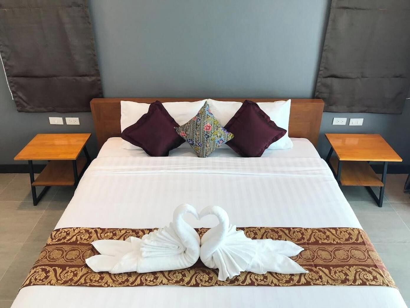 A hotel room with a bed, two bedside tables, and a decorative swan towel on the bed.