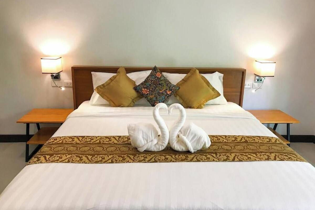 Une chambre d’hôtel avec un lit, deux tables de chevet et des lampes fixées au mur.