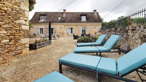 A stone building with a gravel patio, outdoor seating, and a stone wall.