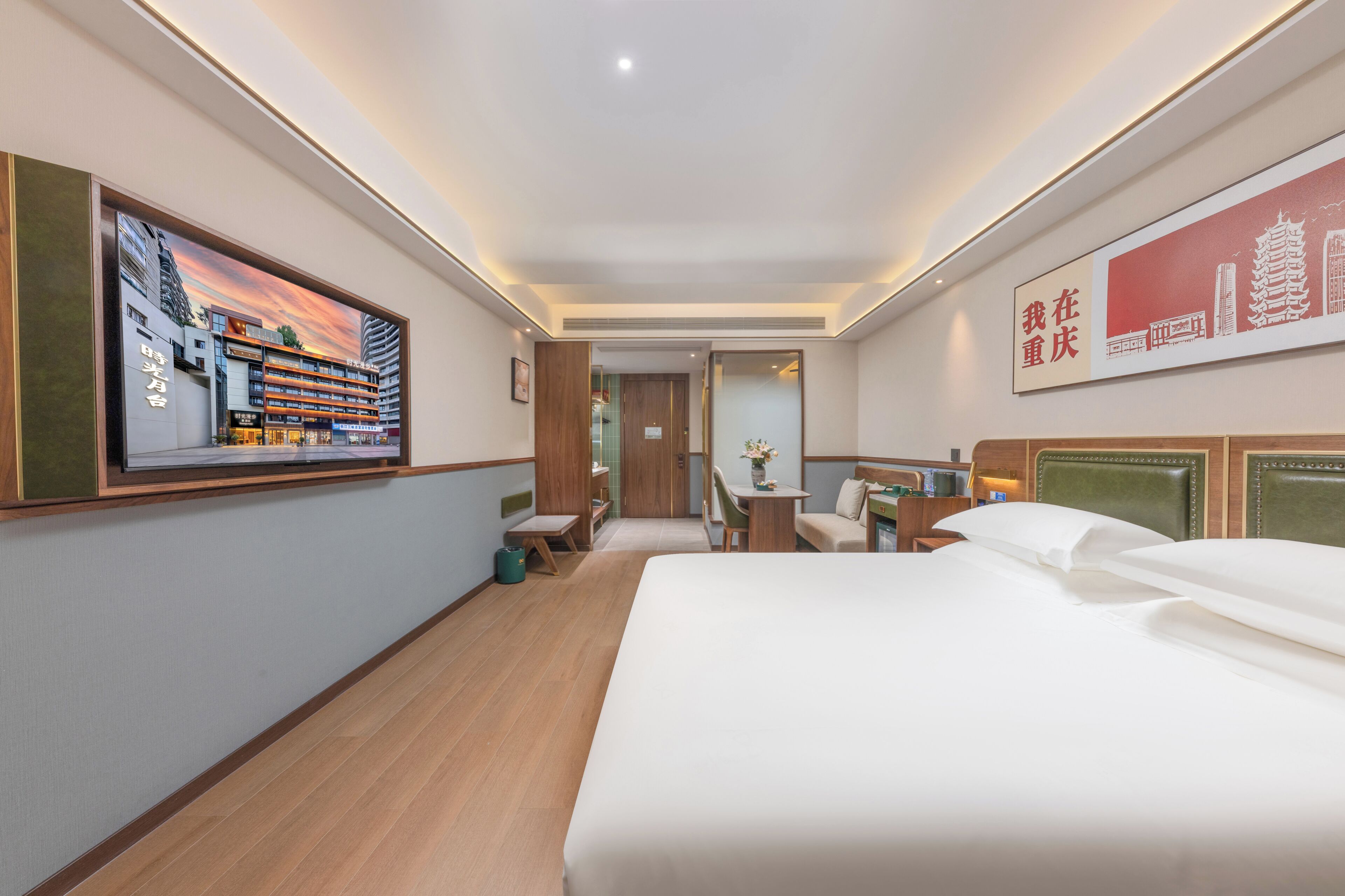 Ein Hotelzimmer mit Bett, Schreibtisch, Stuhl, kleinem Tisch, einem Bild an der Wand und einer Tür zu einem anderen Raum.