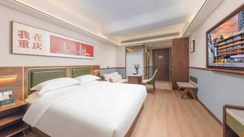 A hotel room with a large bed, a desk, a chair, and a TV screen displaying a cityscape.