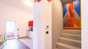 A modern interior with a staircase, a kitchen area, and a colorful wall mural. - Wide and Arty at Spanish Quarter (Naples)
