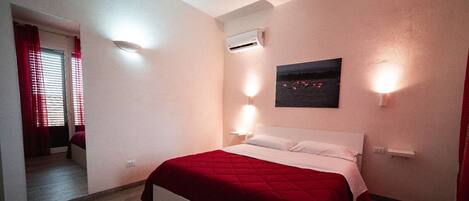 Un dormitorio con cama, aire acondicionado de pared y un cuadro de flamencos.