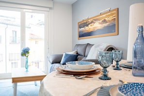 Un comedor con una mesa dispuesta para dos personas, un florero con flores y un cuadro en la pared.