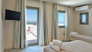 Habitación de hotel con balcón, televisión, cama y aire acondicionado.