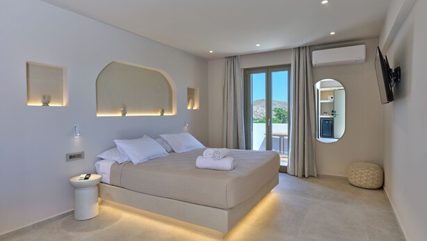 Un dormitorio moderno con una cama grande, mesitas de noche, un espejo y vistas al exterior.