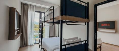 A bunk bed room with a TV and a view of the outdoors.