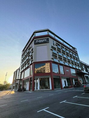 Et hotel med flere etager, med et tydeligt skilt, der viser 'PUREJOY HOTEL'.