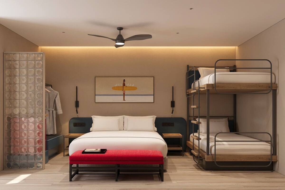 A bedroom with a bunk bed, a single bed, a ceiling fan, a wall-mounted artwork, and a nightstand.