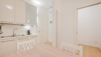 Une cuisine moderne avec des meubles blancs, un évier et une table à manger avec des chaises.