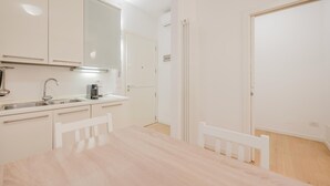 Μια σύγχρονη κουζίνα με λευκά ντουλάπια, έναν νεροχύτη και έναν πάγκο.