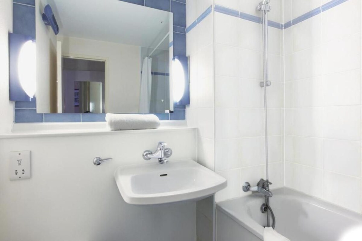 Un baño con lavamanos, espejo y ducha.