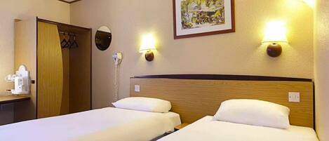 A hotel room with two beds, a bedside table, a mirror, a painting on the wall, and a phone on the wall.