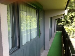 A corridor with a green mat, a door with a window, and a view of greenery outside. - The Beacon Hotel Cardiff (Cardiff)