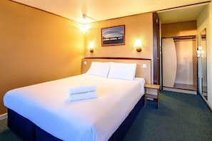 A hotel room with a bed, two bedside lamps, a framed picture on the wall, and a door leading to a closet.