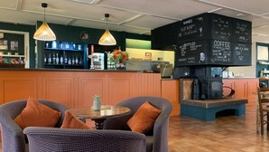 Zona bar con posti a sedere, una macchina da caffè e una bacheca dei menu.