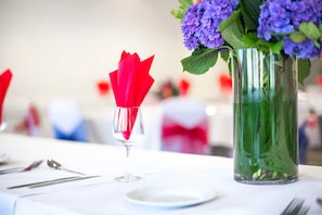A table set with a clear glass, a red napkin, a clear glass with a green plant, and a clear glass with a purple plant.