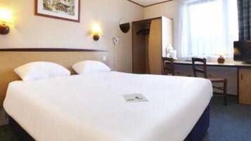 A hotel room with a bed, desk, chair, television, and wall-mounted lights.