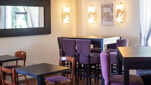 A dining area with tables and chairs, wall-mounted light fixtures, and framed pictures on the wall. - The Raceby Hotel, Doncaster (Doncaster)