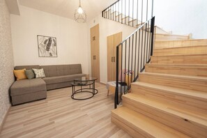 Ein modernes Wohnzimmer mit einer Couch, einem Glastisch und einer Treppe mit Holzbodenstufen.