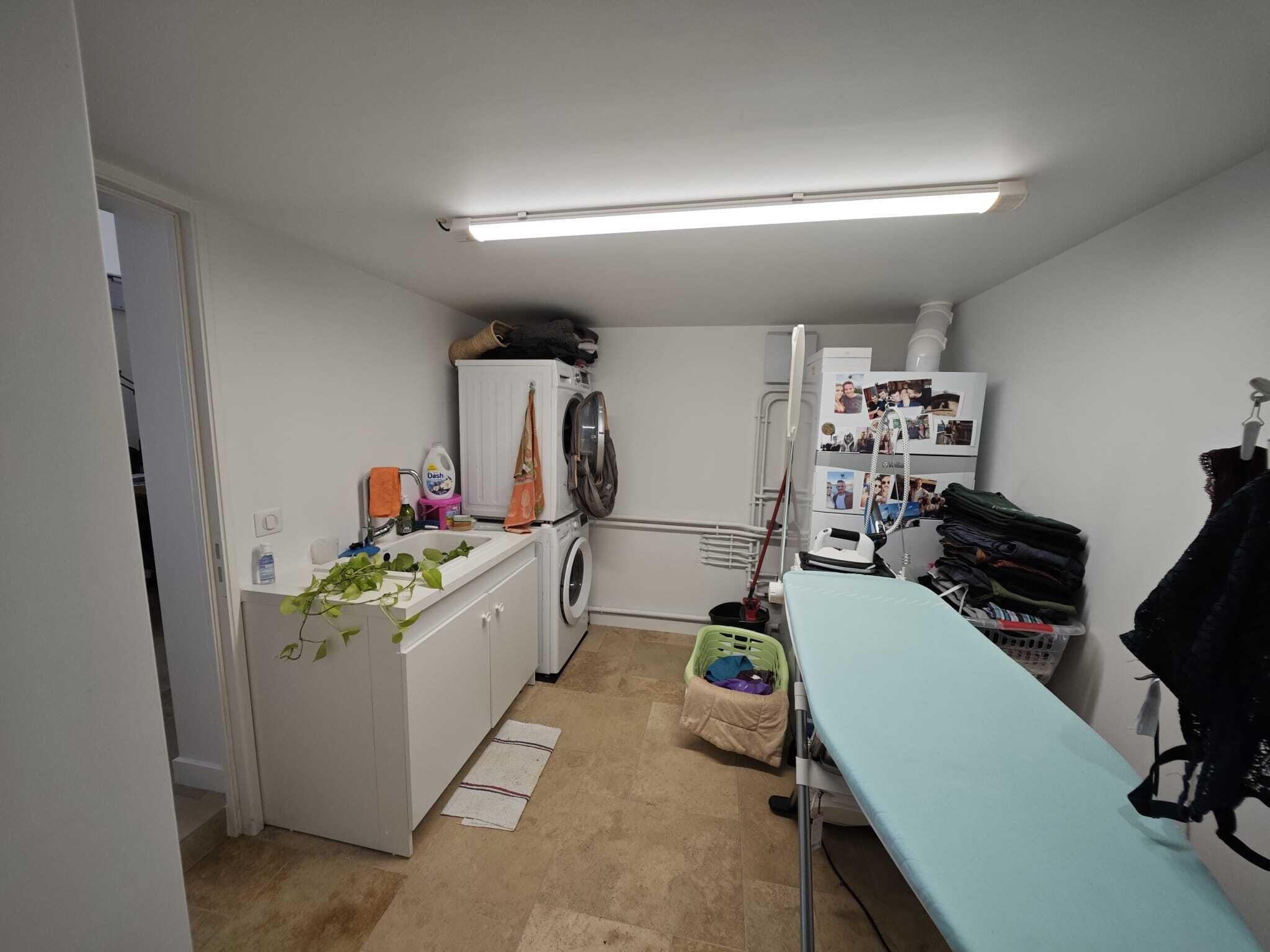 A compact laundry room with a washing machine, dryer, and ironing station.