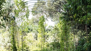 A pathway with irregularly shaped stones and a metal archway surrounded by dense greenery.