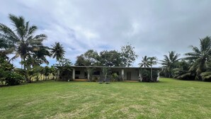 A house with a spacious lawn, surrounded by palm trees and other vegetation. - Muri Homeland Villa N1 (Ngatangiia District)