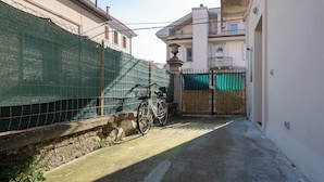 A narrow alleyway with a bicycle, a green fence, and buildings with balconies. - Stefania Flat - 5 minuti dalla spiaggia (Pescara)