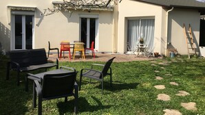 Una casa con patio, muebles de exterior y un árbol.
