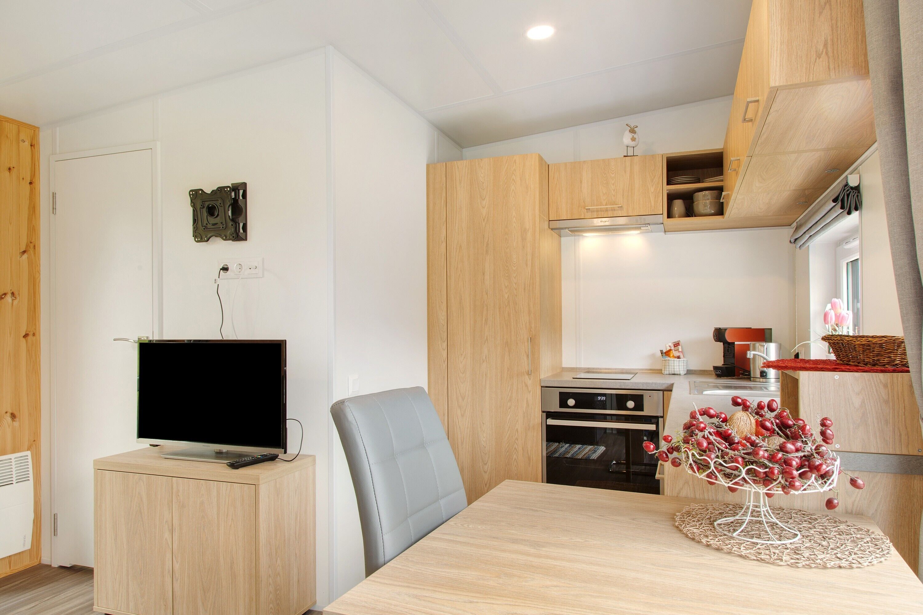 Eine moderne Küche mit Holzausbau, einem eingebauten Backofen und einem Essbereich mit Tisch und Stuhl.