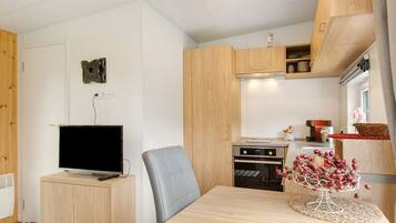 Eine moderne Küche mit Holzausbau, einem eingebauten Backofen und einem Essbereich mit Tisch und Stuhl.