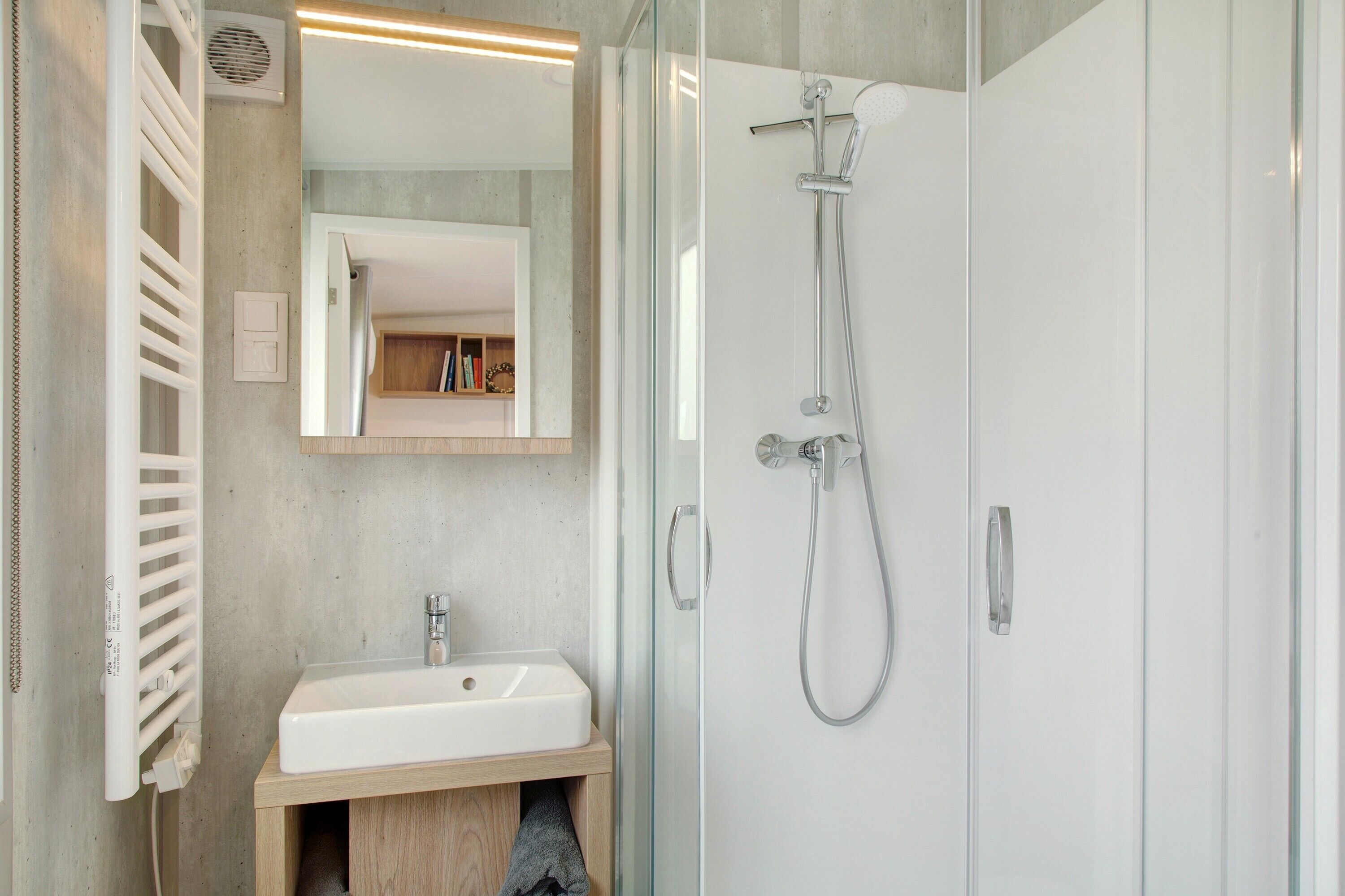 Ein modernes Badezimmer mit Duschkabine aus Glas, einem weißen Waschbecken und einem Holzwaschtisch.
