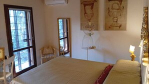 A room with a bed, a chair, a window, and wall-mounted artwork. - The three owls of san gimignano (San Gimignano)