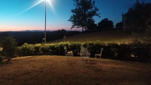 A grassy outdoor area with two metal chairs and a lamppost. - The three owls of san gimignano (San Gimignano)