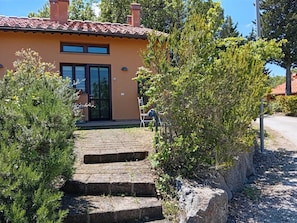 Una casa con techo de tejas, puerta principal y entrada empavedada con escalones.