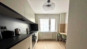 A modern kitchen with a built-in oven, a kettle, and a coffee maker. - New Apartment Just 1 Min from the Basel Border (Saint-Louis)