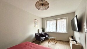A bedroom with a bed, a desk, a chair, a TV, and a window. - New Apartment Just 1 Min from the Basel Border (Saint-Louis)