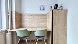 A small, modern kitchen with two green chairs, a wooden cabinet, and a window with a view. - New Apartment Just 1 Min from the Basel Border (Saint-Louis)