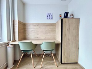 Una cocina pequeña y moderna con dos sillas verdes, un armario de madera y una ventana con vistas.