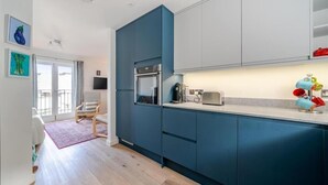Une cuisine moderne avec des armoires bleues, un four encastré et une machine à café.