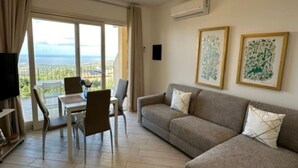 A living room with a sofa, chairs, a TV, and artwork on the walls. - Affittimoderni Red Island Elite PATI16 (Trinità d´Agultu e Vignola)