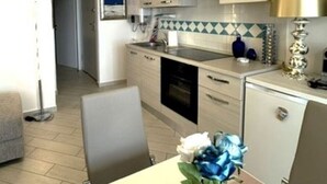 A modern kitchen with a dining area, featuring a central island, built-in cabinets, and a decorative vase with flowers. - Affittimoderni Red Island Elite PATI16 (Trinità d´Agultu e Vignola)