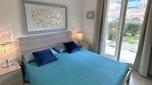 A bedroom with a bed, nightstands, a wall-mounted artwork, and a view through a glass door. - Affittimoderni Red Island Elite PATI16 (Trinità d´Agultu e Vignola)