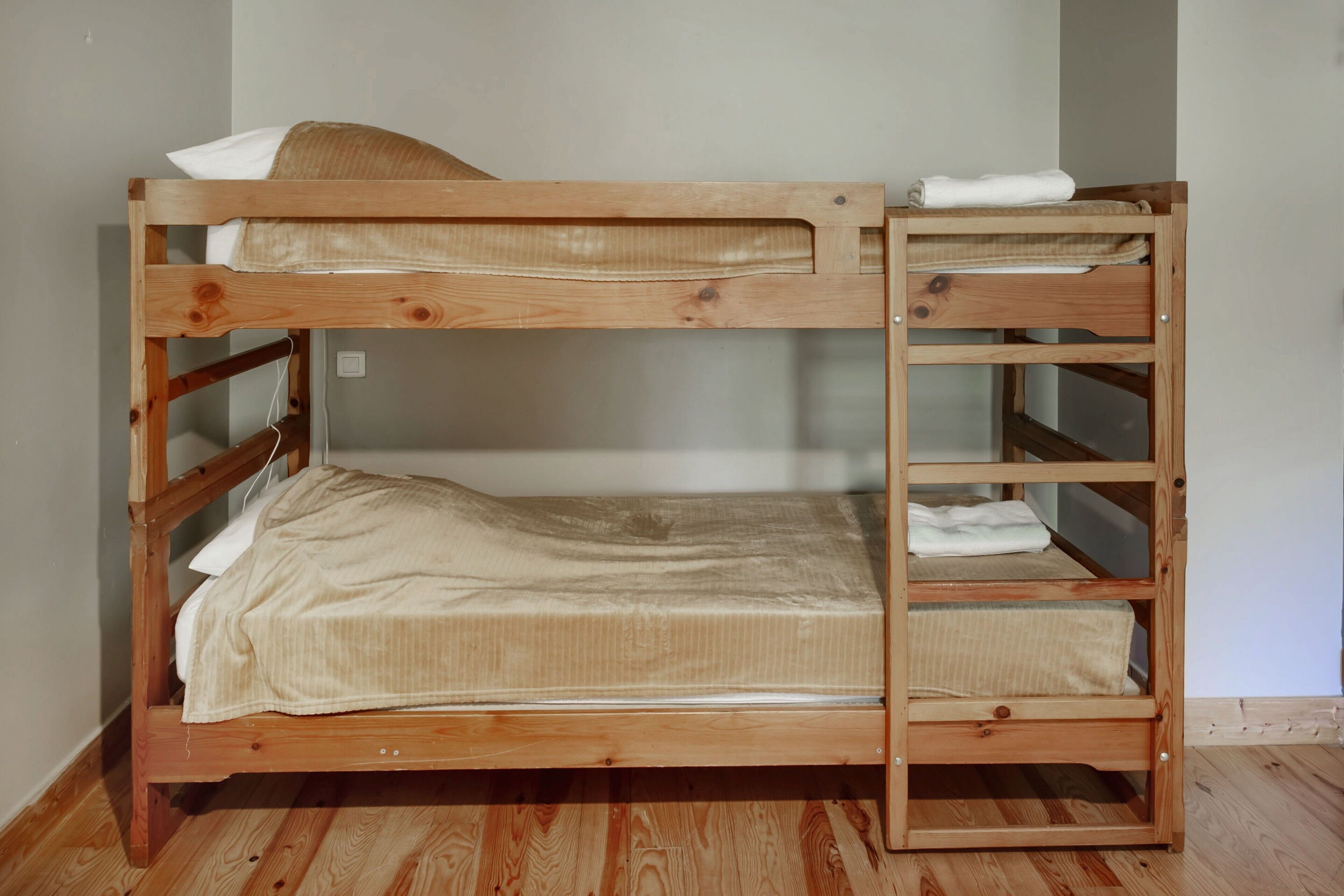 Een stapelbed met houten frame, een matras en een kussen.